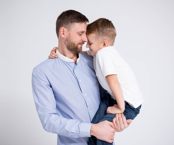 portrait of young father and cute little son hugging over white background - Photo, Image