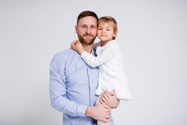 portrait of young father and little daughter hugging over white background - Photo, Image