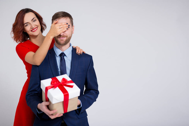 Día de San Valentín, Navidad o concepto sorpresa - mujer sorprendiendo a su novio con espacio de regalo y copia sobre fondo blanco
 - Foto, Imagen