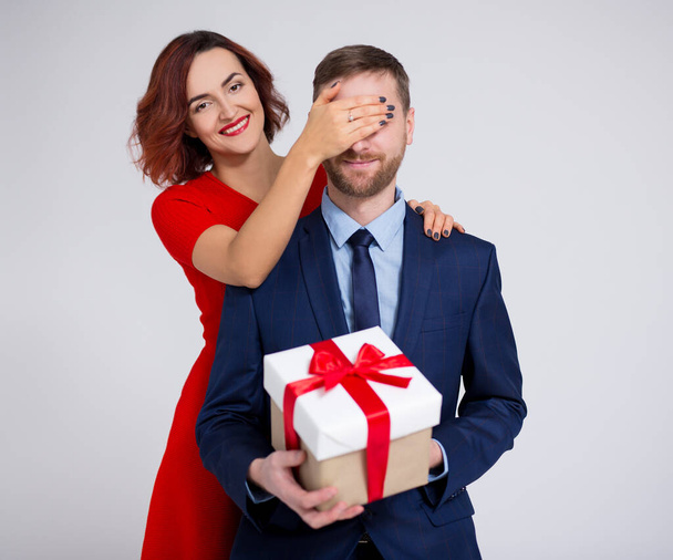 Valentine's day, christmas or surprise concept - woman surprising her boyfriend with gift over white background - Foto, Imagem