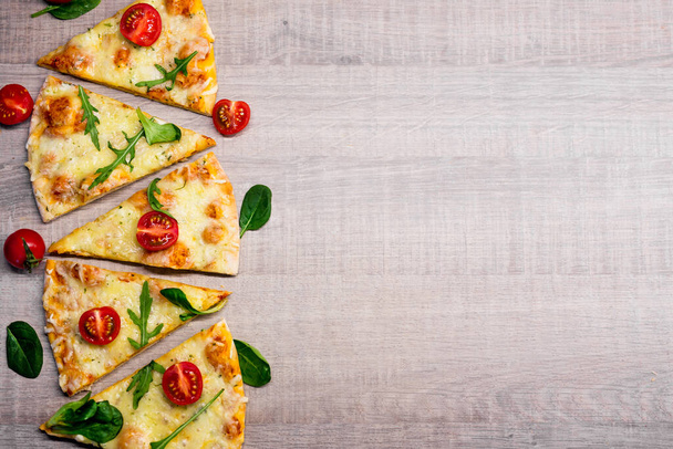 Scheiben leckerer Pizza mit Tomaten und Kräutern über hölzernem Tischhintergrund mit Kopierraum - Foto, Bild