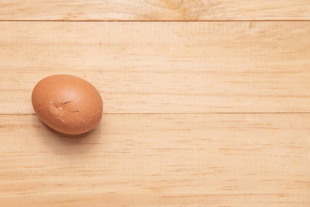 One of broken chicken egg on a light brown wooden background, Top view with copy space - Photo, Image
