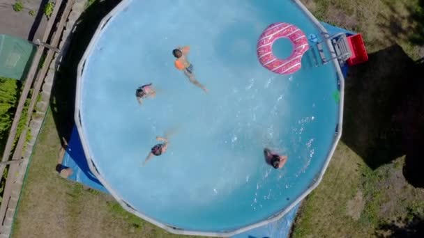 Küçük beyaz çocuklar bahçede yüzme havuzunda eğleniyorlardı. Üst Manzara. Çocuklar ve çocuklar için serin yaz tatilleri. Suda oyunlar. Pembe donat. 4k - Video, Çekim
