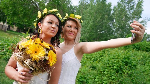Dos damas de honor tomando selfies en una boda. La novia se toma una selfie con su hermana. Dos novias tomando una foto en su boda con el teléfono
. - Foto, imagen