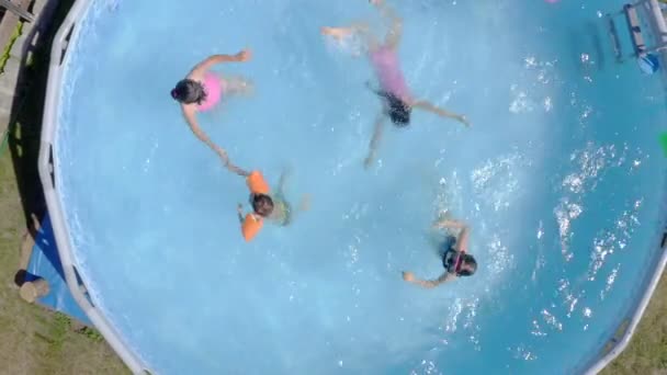 Счастливые маленькие кавказские детишки веселятся в бассейне в саду. Вид сверху. Cool летний отдых для детей и детей. Игры на воде. Розовый донат. 4k - Кадры, видео