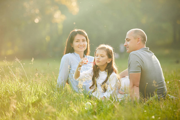 happy family with child girl blow soap bubbles - Fotoğraf, Görsel