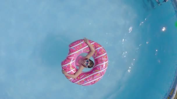 Happy little caucasian kids having fun in a swimming pool in a garden. Top view. Cool summer holidays for children and kids. Games on the water. Pink donat. 4k - Footage, Video