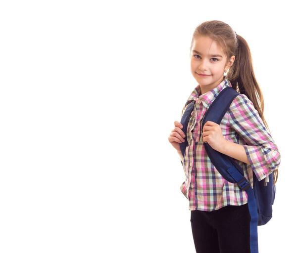 Iskoláslány táskával a hátán, kamerába néz. - Fotó, kép