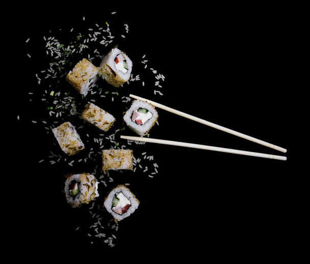 flying up sushi california with rice on a black background close-up with exciting bamboo chopsticks for sushi - Foto, immagini