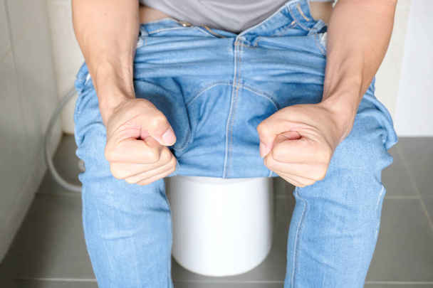 Un homme assis dans la cuvette des toilettes. Dans la salle de bain, sa maison est malheureuse avec la constipation, la diarrhée, l'intoxication alimentaire, la santé et les concepts médicaux. - Photo, image