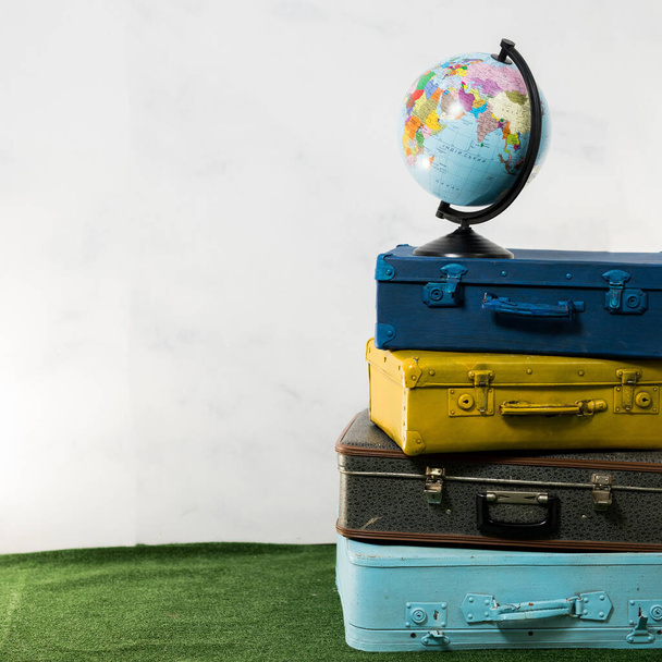 Viagens ou conceito de turismo. Globo isolado em quatro malas castanhas amarelas azuis vintage
 - Foto, Imagem