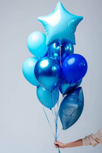 Composition of dark blue, blue, transparent helium balloons and two sapphirine star in the hand of a woman on a white background. - Zdjęcie, obraz