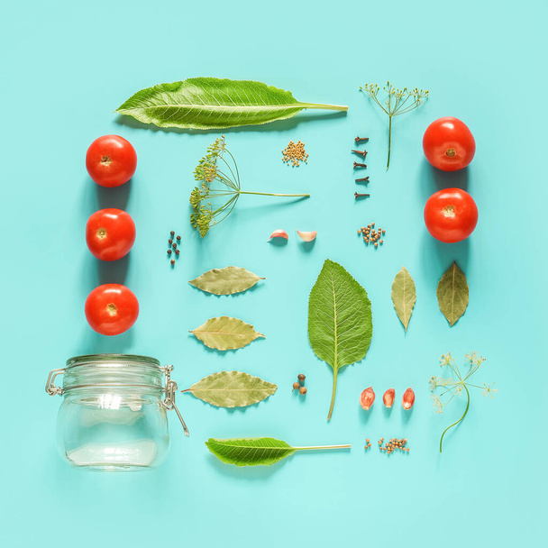 Pickled tomatoes. Ingredients for marinated tomatoes and glass jar on blue background. Concept culinary recipe preservation of vegetables in harvest season. Creative flat lay Top view Copy space. - Foto, Imagen