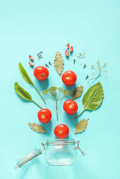 Pickled tomatoes. Flying ingredients for marinated tomatoes and glass jar on blue background. Concept culinary recipe preservation of vegetables in harvest season. Creative flat lay Top view. - Foto, Imagen