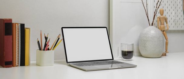 Vue rapprochée du bureau moderne avec ordinateur portable, papeterie, livres, tasse à café et décorations  - Photo, image