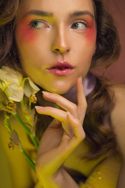 Luxury girl with beautiful yellow-pink make-up and with yellow flowers on a pink background. Good for beauty salons, banners, posters, flyers. - Fotografie, Obrázek