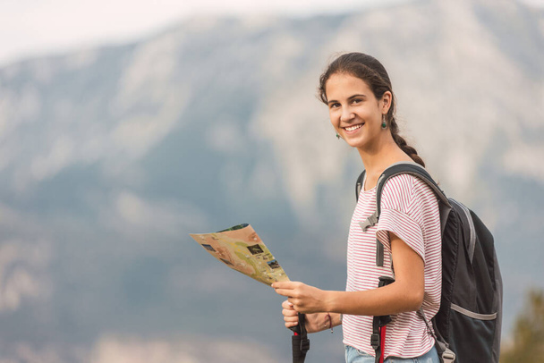 турист с рюкзаком и палками, смотрящий на камеру в красивом месте с горами на заднем плане
 - Фото, изображение