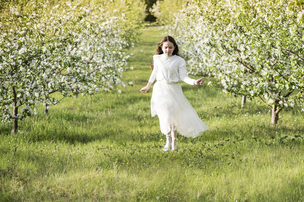 A beautiful  girl runs through a flowering apple garden in the spring. Child  in a blooming garden at sunse - Fotoğraf, Görsel