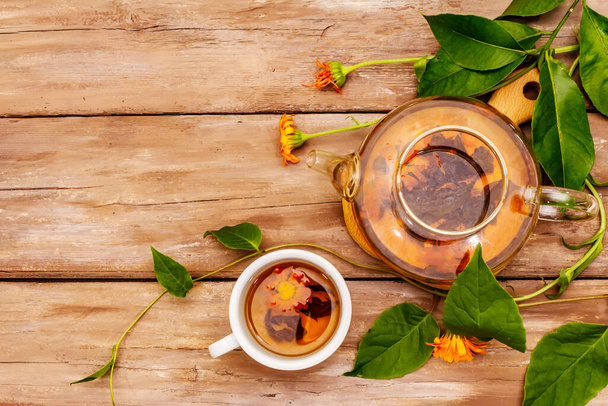 Friss körömvirág tea. Alternatív gyógyászat, fa táblák háttér, felülnézet - Fotó, kép