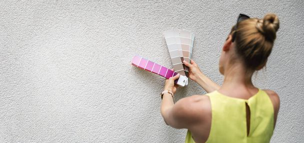 woman choosing paint color from swatch for house stucco exterior facade. copy space - Фото, изображение