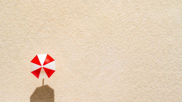 Luftaufnahme eines Sandstrandes mit einem roten Sonnenschirm. Sommer- und Reisekonzept. Minimalismus - Foto, Bild