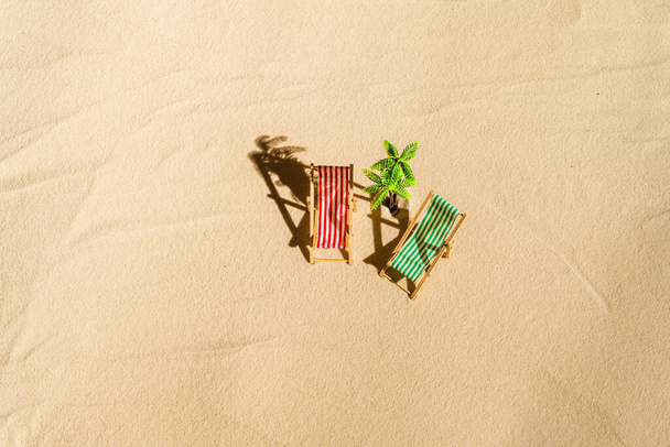 Aerial view of two deck chair, sunbed, lounge, palm tree on sandy beach. Summer and travel concept. Minimalism - Zdjęcie, obraz