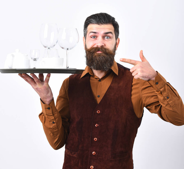 Man with beard holds tray with dishes on white background. - Foto, afbeelding