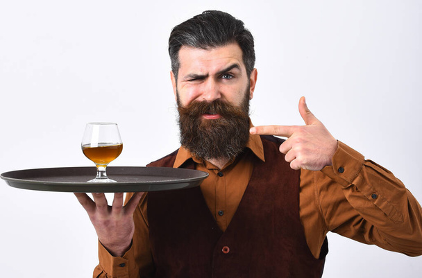 Barman with proud face and in vintage vest serves cognac. - Φωτογραφία, εικόνα