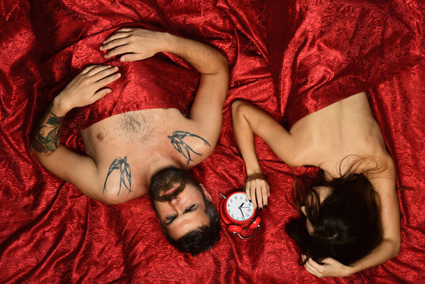 Man and woman with half covered bodies lie near clock - Φωτογραφία, εικόνα
