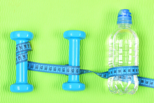 Two plastic dumbbells and bottle. Healthy lifestyle and training concept. - Foto, afbeelding