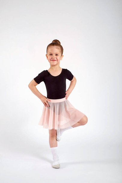 Little girl dressed in dance uniform is dancing over a white background in the studio. - 写真・画像