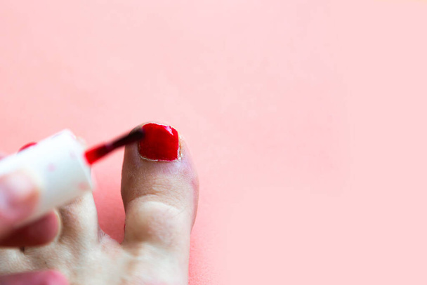 Woman paints her toenails red polish, view from above - Zdjęcie, obraz