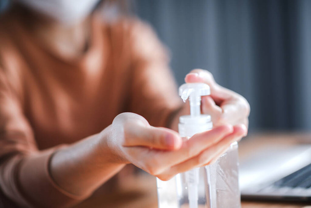 Arbeiten von zu Hause aus, Coronavirus-Schutz, Nahaufnahme Reinigung ihrer Hände mit Desinfektionsgelen, Frau in Quarantäne wegen Coronavirus mit Schutzmaske. - Foto, Bild