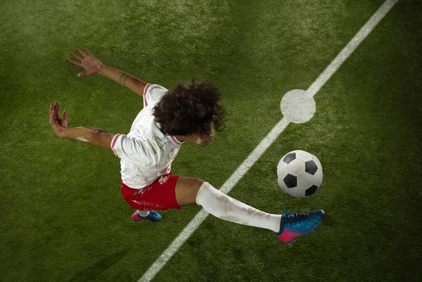 Top view of caucasian football or soccer player on green background of grass in action and motion - Fotó, kép