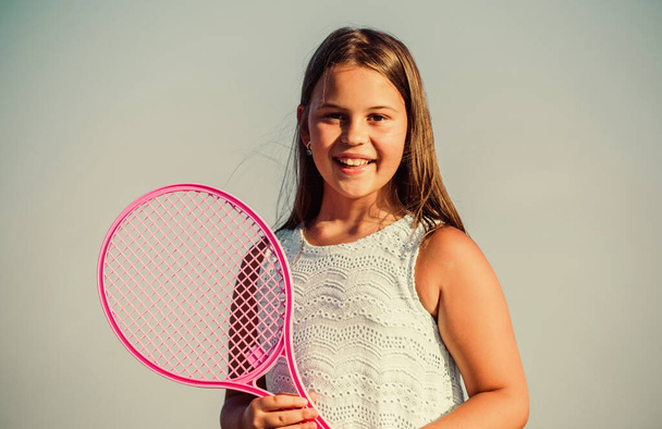 Child play tennis blue sky background. Sporty kid. Small girl with pink tennis racket. Summer leisure. Sport game. Playful cheerful kid. Happy childhood. Positive. Emotional baby. Active life - Photo, image