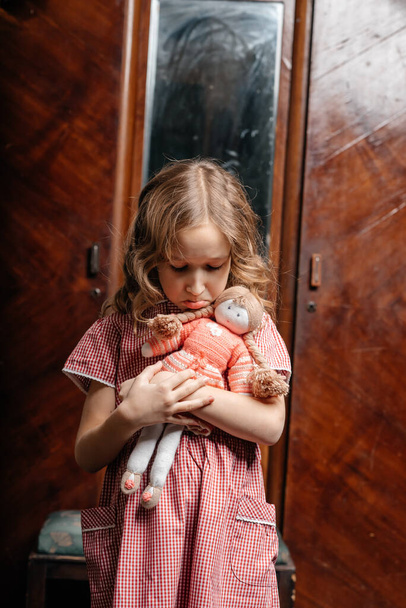 little girl in a dress posing with her doll in old room - Foto, afbeelding