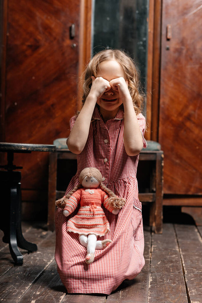 little girl in a dress posing with her doll in old room - Photo, image