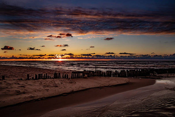 belo pôr do sol colorido sobre o mar Báltico polonês com nuvens de céu escuro e quebra-mar
 - Foto, Imagem