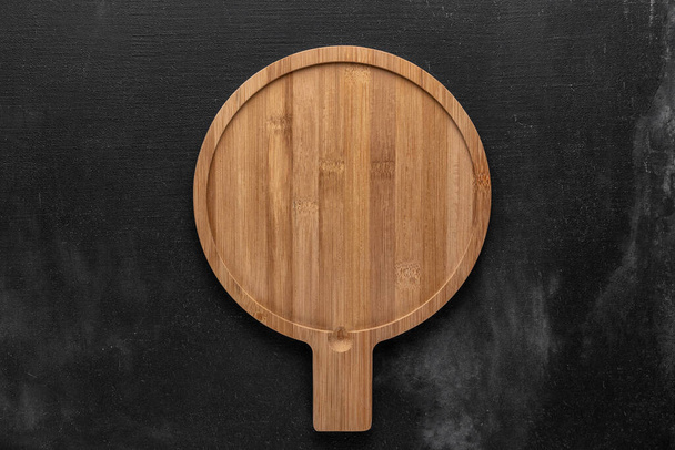 round wooden cutting board in the middle of a gray background. free space for your text, top view - Φωτογραφία, εικόνα