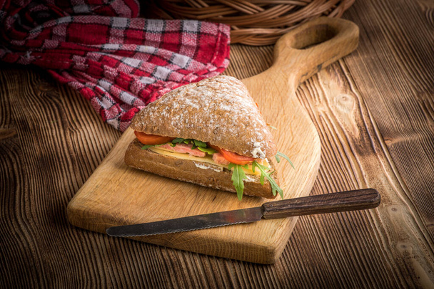 Triangular sandwich with cheese, ham and tomato on a wooden table. - Valokuva, kuva