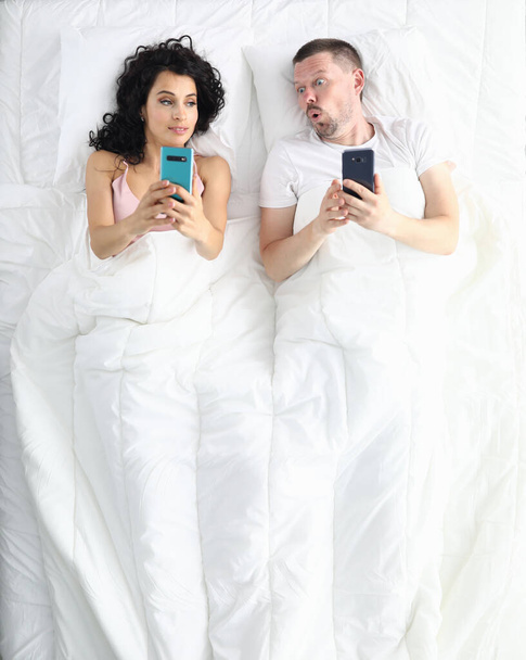Wife and husband lie on bed top view portrait - Foto, imagen
