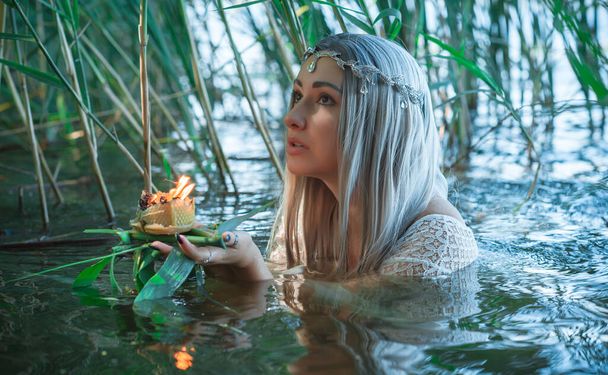 Oude Europese magie, mystieke heidense scene, vrouw in het meer, rituelen. Magische waarzeggerij door kaarsen van was op het water, ritueel. Helderziende, waarzegster - Foto, afbeelding