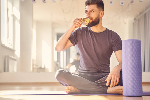 Handsome young man drinking tea in yoga studio - Foto, Imagem