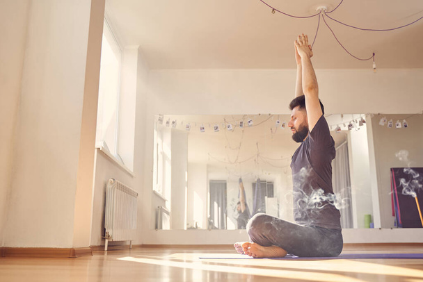 Bearded young man doing yoga exercise in studio - Photo, image
