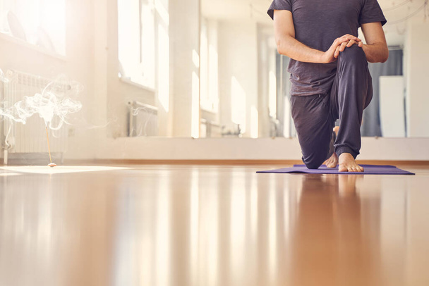 Young man standing in yoga position on yoga mat - Foto, imagen