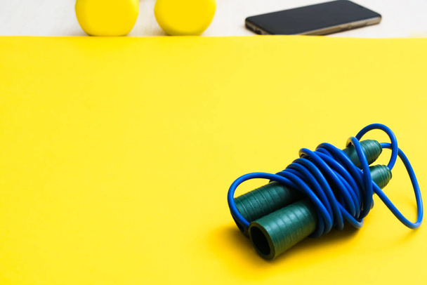 Blue fitness skipping rope for jumping with plastic handles on yellow background - Foto, Imagen
