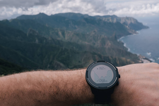 Runner checking progress on smart watch. Fit male runner exercise training and jumping outdoors in beautiful mountain nature landscape - Photo, Image