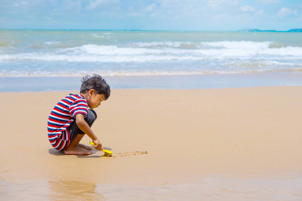 Little asian boy play with toy and sand on the beach. - Foto, imagen