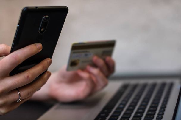 Mãos segurando cartão de crédito e usando smartphone e laptop. Compras online, conceito de pagamento on-line
 - Foto, Imagem