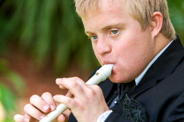 Обличчя хлопчика з обмеженими можливостями, який грає на флейті
. - Фото, зображення